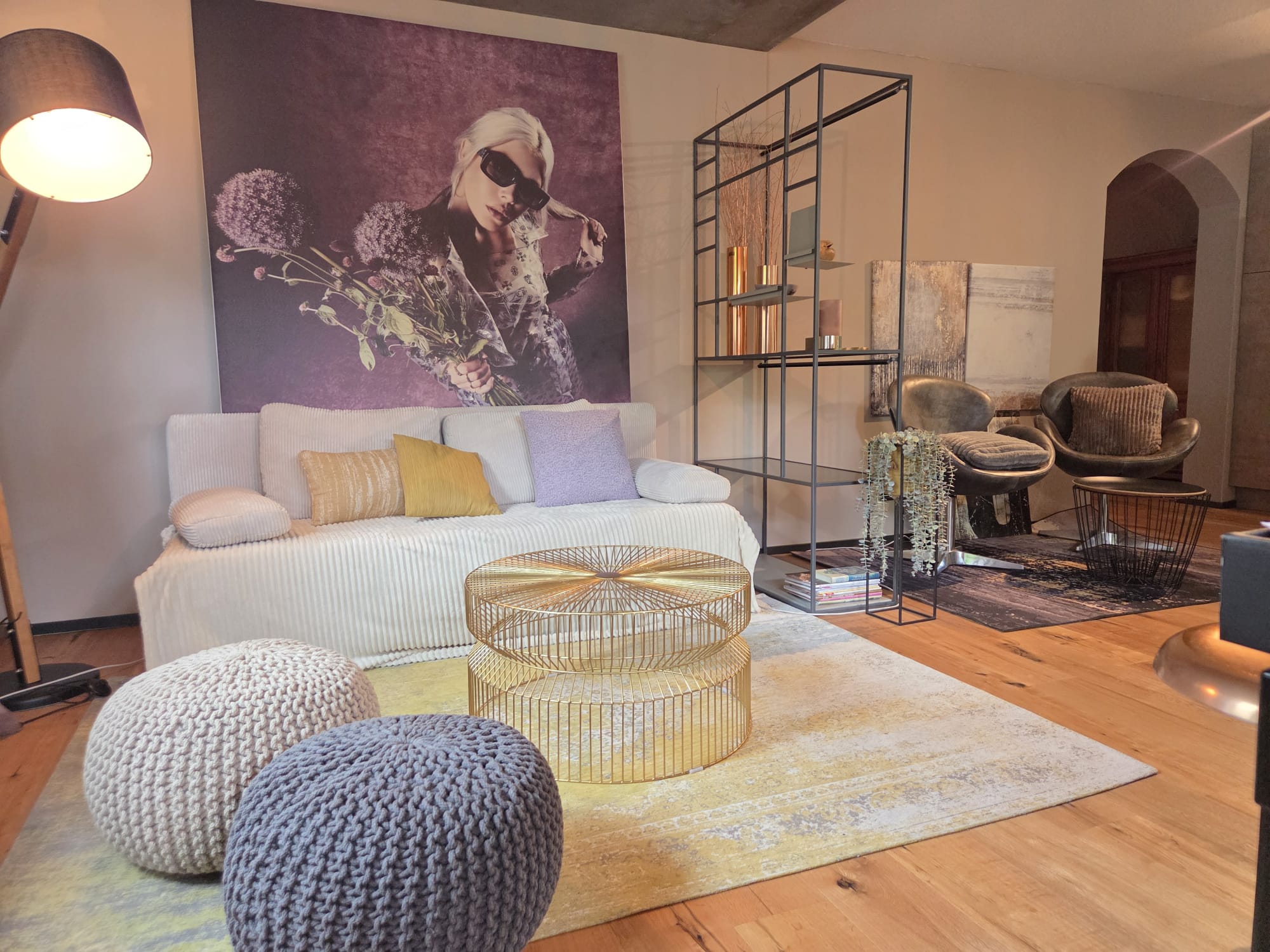 Künstlerwohnung in Langenargen am Bodensee, Wohnraum mit großformatiger Kunst, Messing-Coffeetable und schwarzem Metallregal